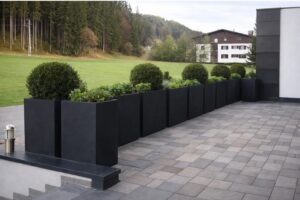 Eine Terrasse mit einer Galerie rechteckiger, hoher, anthrazitfarbener Pflanzkübel von Blumentrog-Flexi - schlicht, elegant, robust, sowie wetterfest.