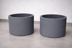 Zwei zylindrische graue Pflanzkübel mit matter Oberfläche und Hartschaumkern von Blumentrog-Flexi.