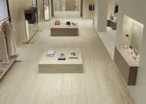 C.Bergmann zeigt einen großen offenen Verkaufsraum mit beige marmorierten Wand- und Bodenfliesen von Atlas Concorde der Serie Marvel Travertine.