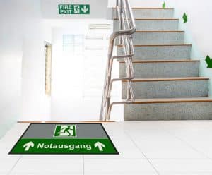 Bedruckte Fußmatte von CWS Hygiene mit dem Hinweis zum Notausgang.