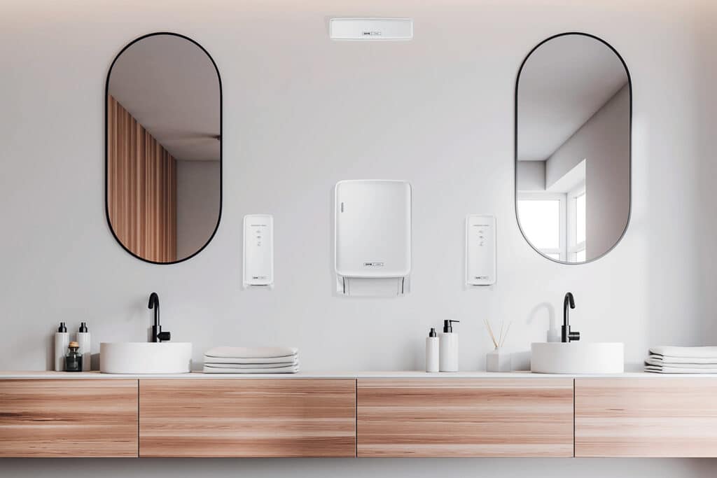 CWS Hygiene zeigt ein modernes Badezimmer mit Doppelwaschtisch und an der Wand montierte Handtuchspender und Seifenspender in weiß.