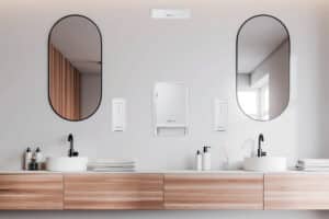 CWS Hygiene zeigt ein modernes Badezimmer mit Doppelwaschtisch und an der Wand montierte Handtuchspender und Seifenspender in weiß.