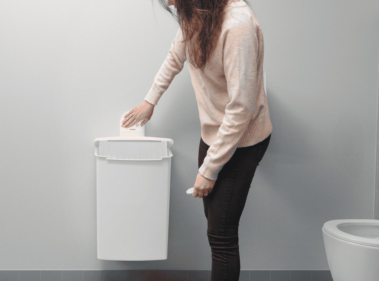 Frau bei der Bedienung des Hygienebehälters mit Touch-Öffner von CWS.