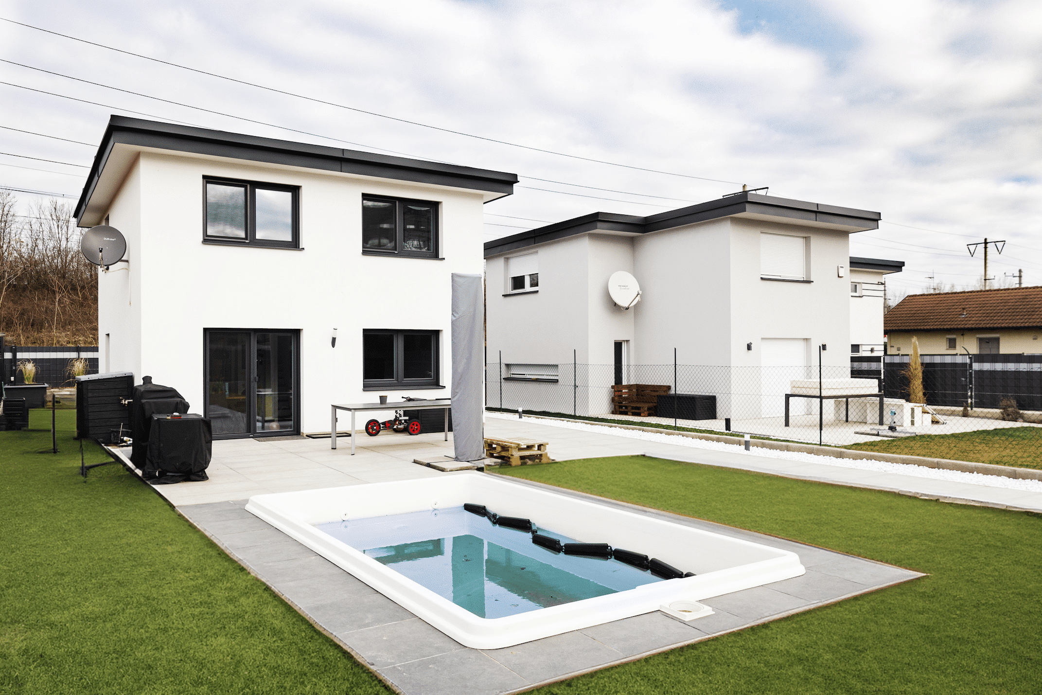 Einfamilienhaus mit weißem Putz, schwarzen Alufenstern und Pool von DIALOG Haus.