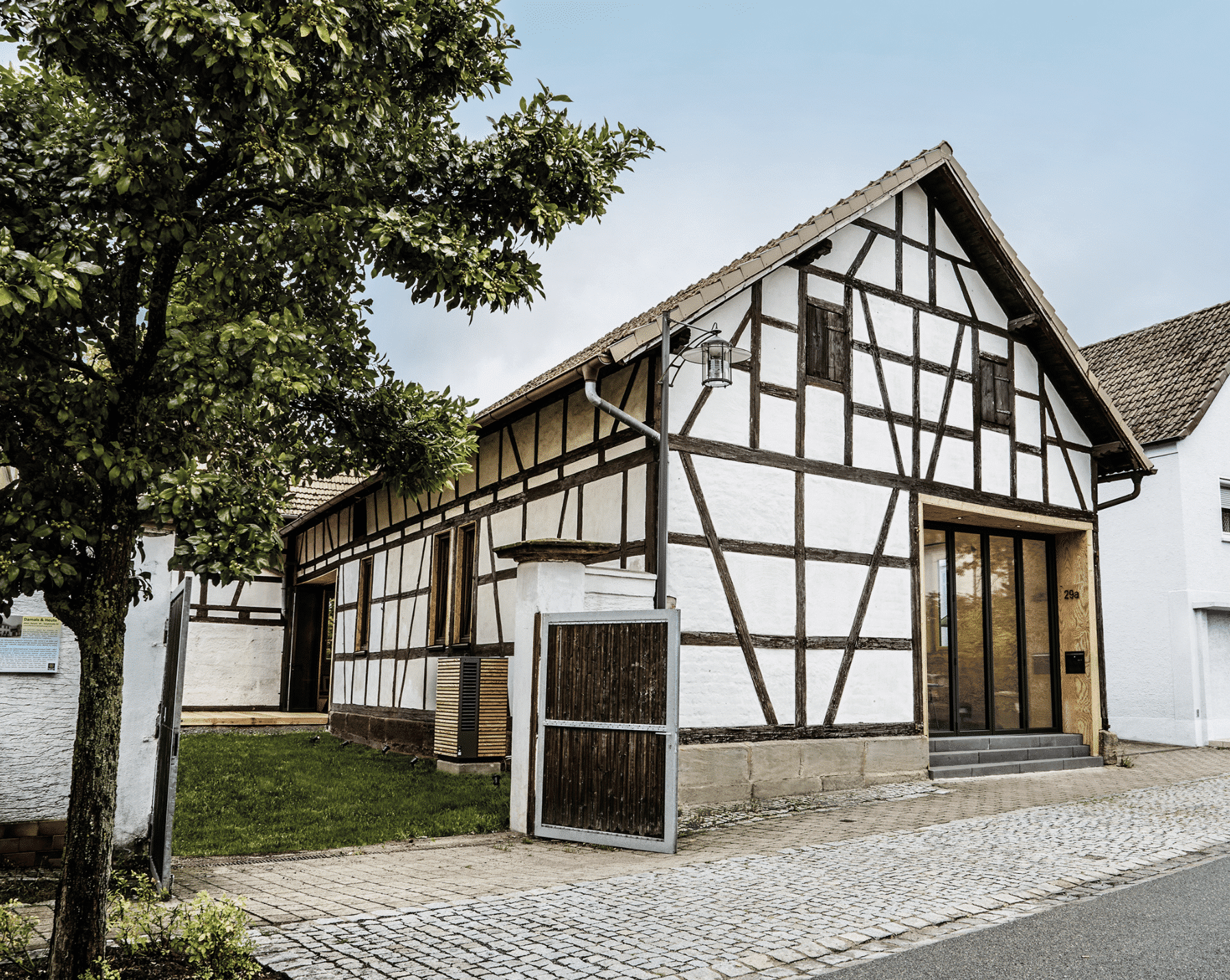 Dimplex zeigt eine Wärmepumpe mit Holzverkleidung im Außenbereich eines älteren Landhauses mit großer Einfahrt.