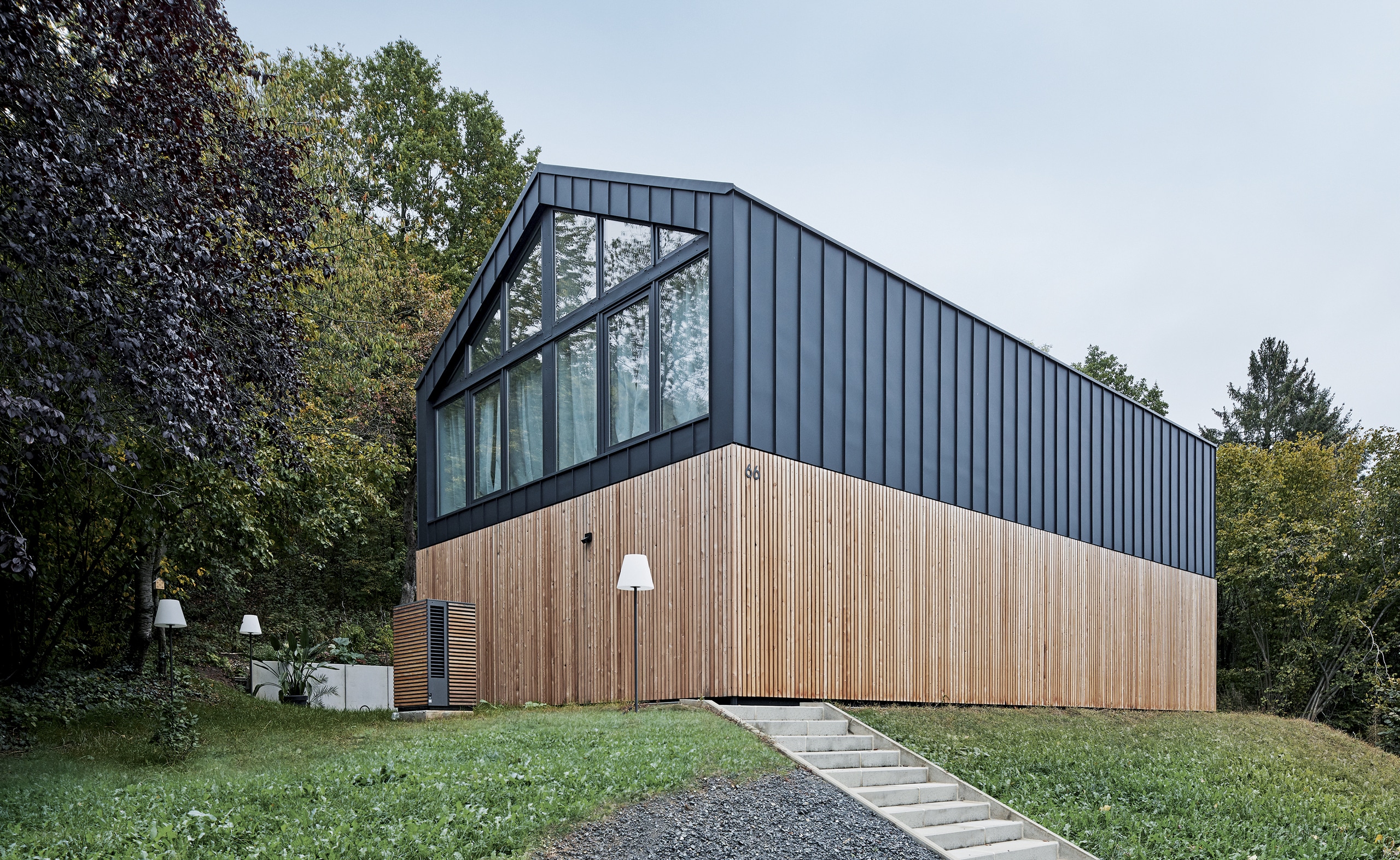 Modernes Gebäude mit anthrazitfarbigem Alu und Holz verkleidet und davor eine Wärmepumpen Außeneinheit im gleichen Design von Dimplex.
