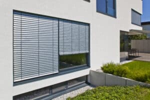 Einfamilienhaus mit bodentiefen Fenstern und silbernen Außenrollläden von DolenzGollner.