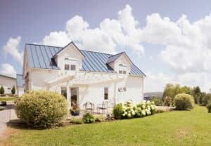 Klassisches Einfamilienhaus mit vertikaler, weisser Fassadenverkleidung aus Holz, Zwerchdach und solarbetriebenen weissen Rollläden von DolenzGollner.