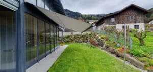 Einfamilienhaus mit Glasfassade und einem fassadenmontierten grauen Sonnensegel von DolenzGollner.