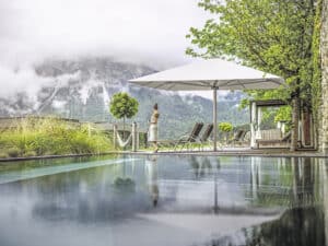 Quadratischer Sonnenschirm mit Aluminiumgestell und weissem Bezug, bodenverankert neben dem Loungebereich eines Schwimmbeckens, von DolenzGollner.