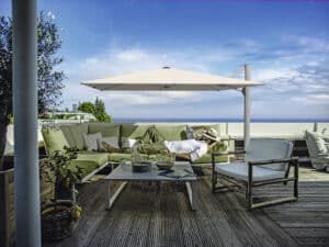Dachterrasse mit einem auf einer Outdoor-Couch schlafenden Mann und einem schwenkbaren, höhenverstellbaren Alu-Sonnenschirm von DolenzGollner.