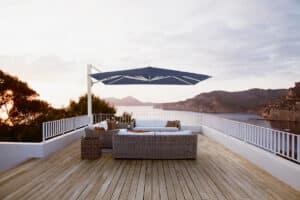Dachterrasse mit Outdoor-Lounge aus Rattan und einem freistehenden, schwenkbaren und höhenverstellbaren Alu-Sonnenschirm mit weissem Gestell und marineblauen Stoff von DolenzGollner.