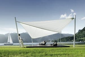 DolenzGollner Sonnenschutztechnik Ing. Wagner GmbH zeigt ein Holzdeck an einem See mit großem, weißen Sonnensegel von Soliday.
