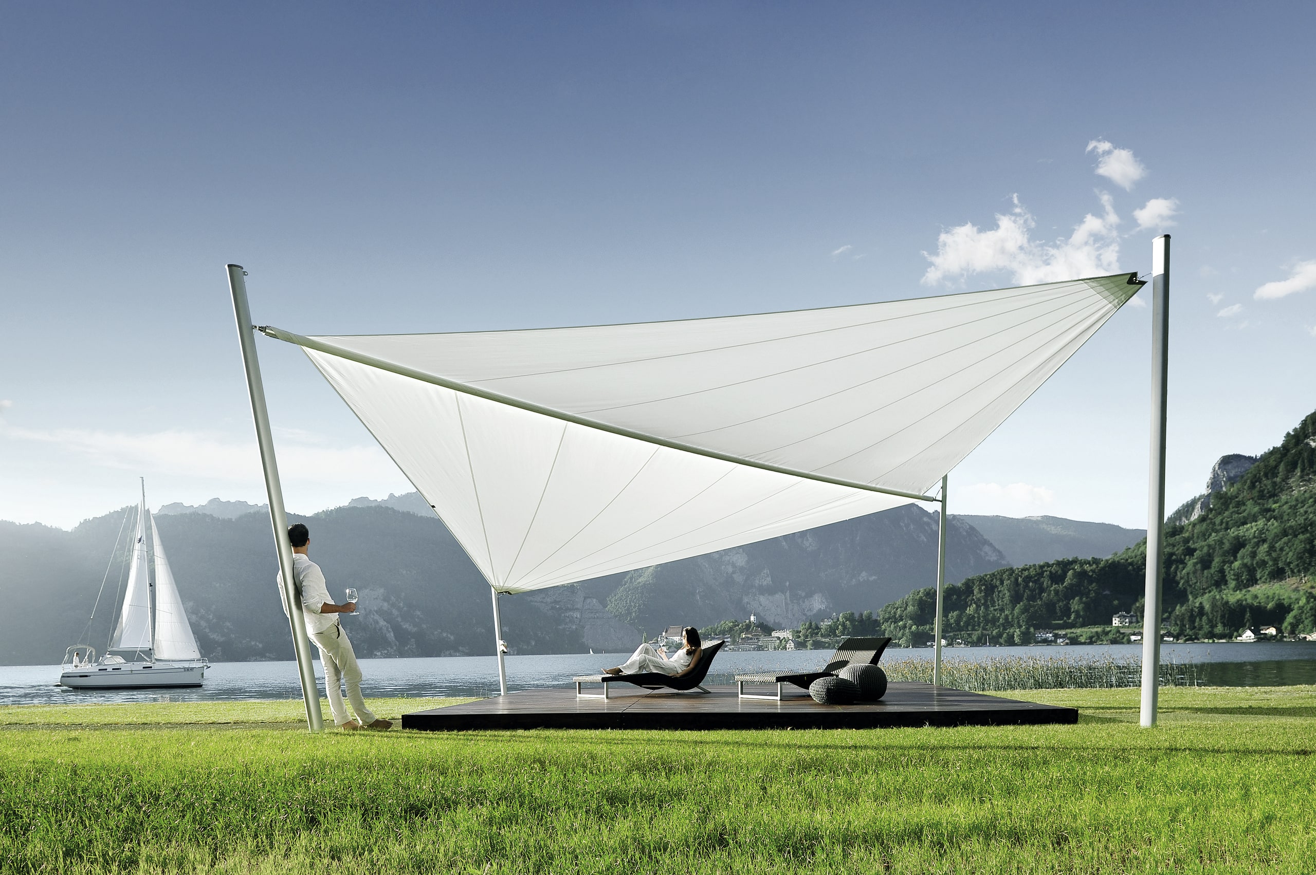 DolenzGollner Sonnenschutztechnik Ing. Wagner GmbH zeigt ein Holzdeck an einem See mit großem, weißen Sonnensegel von Soliday.