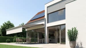 Einfamilienhaus mit Garten, gefliester Terrasse und einer an der Hausfassade montierten elektrischen Gelenkarmmarkise in Beige von DolenzGollner.