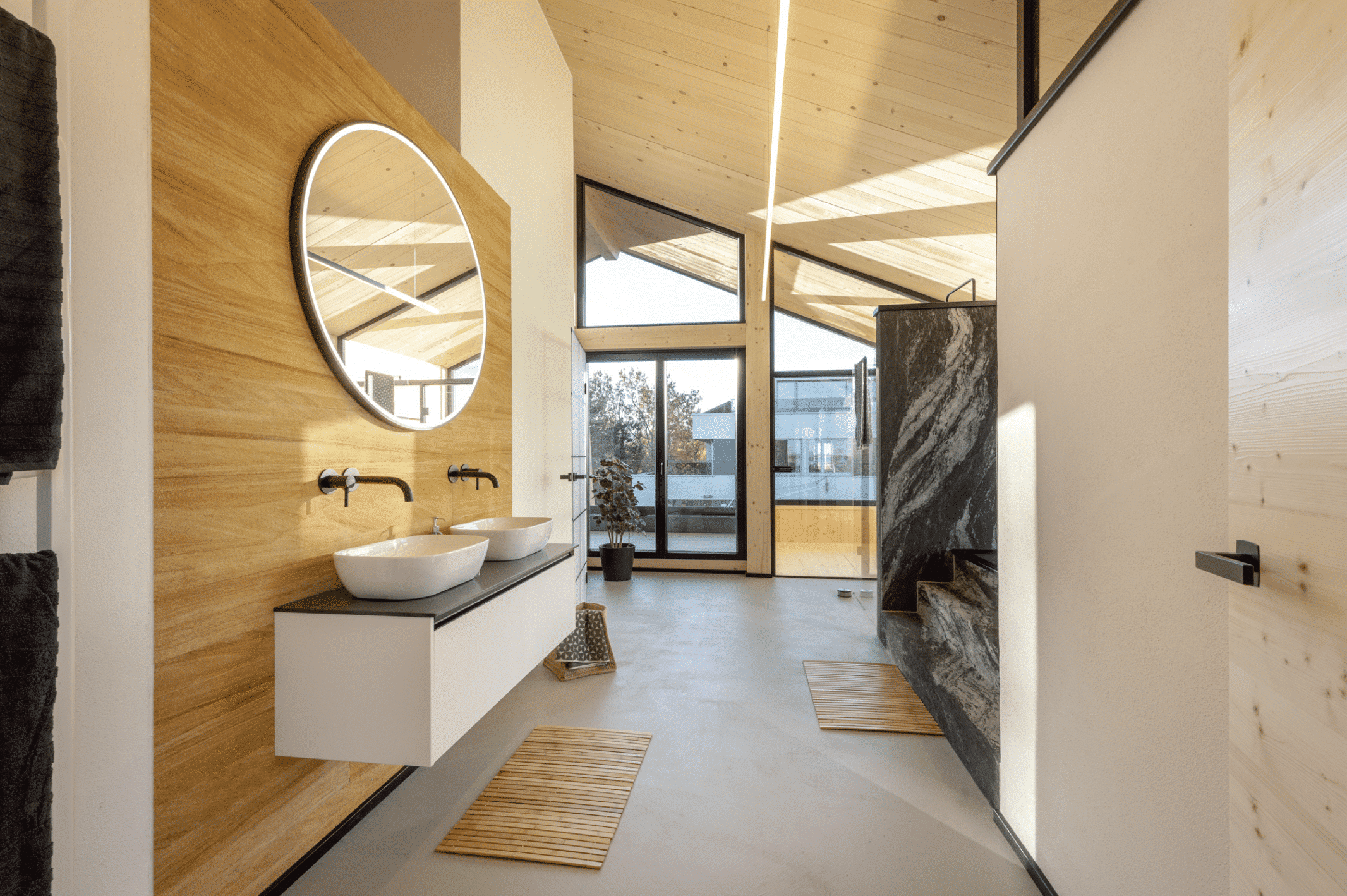 ERLER Haus zeigt eine Badezimmer mit höher Deckenhöhe, viel Fensterfläche, Doppelwaschtisch und Treppen zur Badewanne.