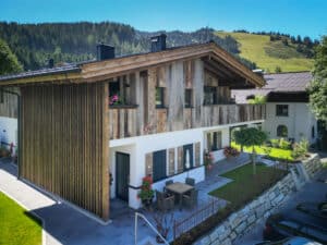 Rustikale Villa mit Fassadenelementen aus Holz, Balkon, Außenaufgang, Holzfensterläden und Außenjalousien von ERLER Haus.