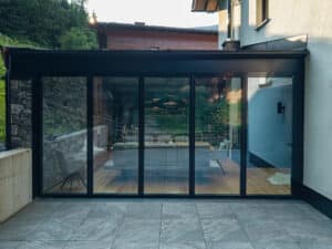 Ein moderner Wintergarten mit direktem Übergang zur gefliesten Terrasse, großzügigen Glasflächen und harmonischer Verbindung von Innen‑ und Außenraum von ERLER  Haus.