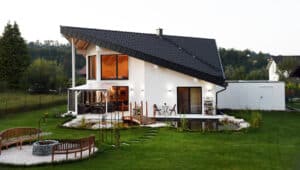 Einfamilienhaus mit Kombinationsdach, großzügiger gefliester Terrasse mit halboffener Pergola-Überdachung und einem romantischem Garten mit Biotop, Brücke und Brunnen von ERLER Haus.