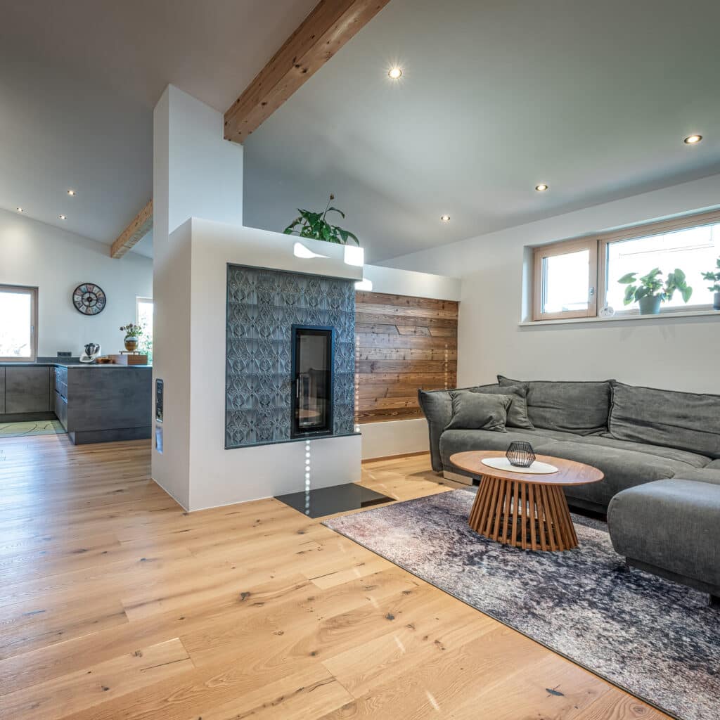 Gemütlicher Wohnbereich mit Kachelofen, Couch und moderner Beleuchtung in einem Erler Haus.
