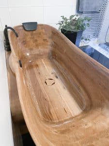 Massivholzbadewanne Relax Comfort von FESTWOOD mit Kopfstütze und schwarzer 4-Loch-Armatur.