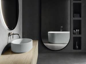 Elegantes Badezimmer mit freistehendem, hellblauem Waschbecken und Badewanne mit gerillter Oberfläche von Fliesendorf.