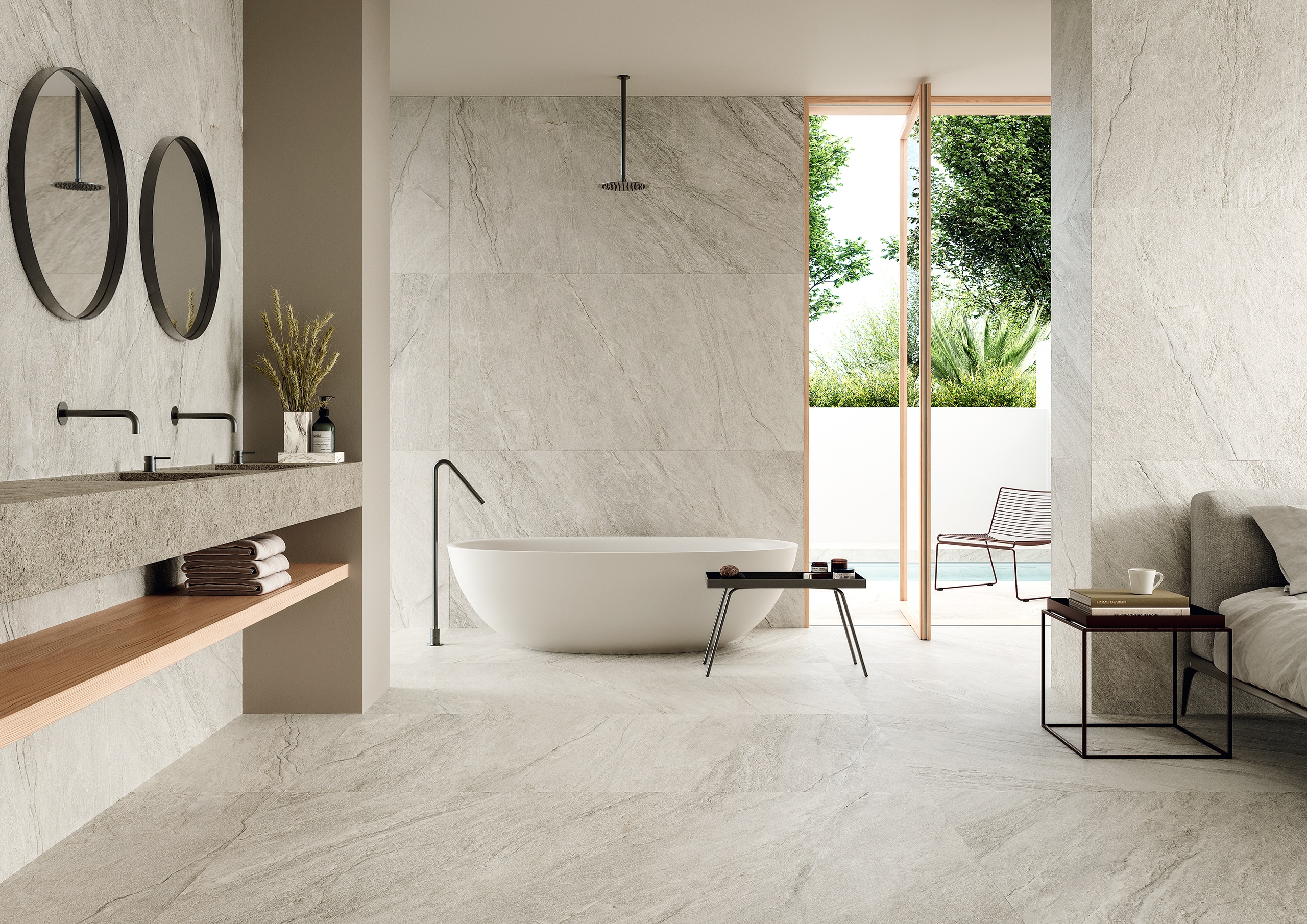 Fliesendorf zeigt eine offenes Badezimmer mit angrenzendem Schlafzimmer mit Wand- und Bodenfliese in XL grau-weiss-marmoriert mit schwebendem Doppelwaschtisch in Steinoptik, freistehender Badewanne und einer Dreh-Kipp-Terrassentür mit Holzrahmen.