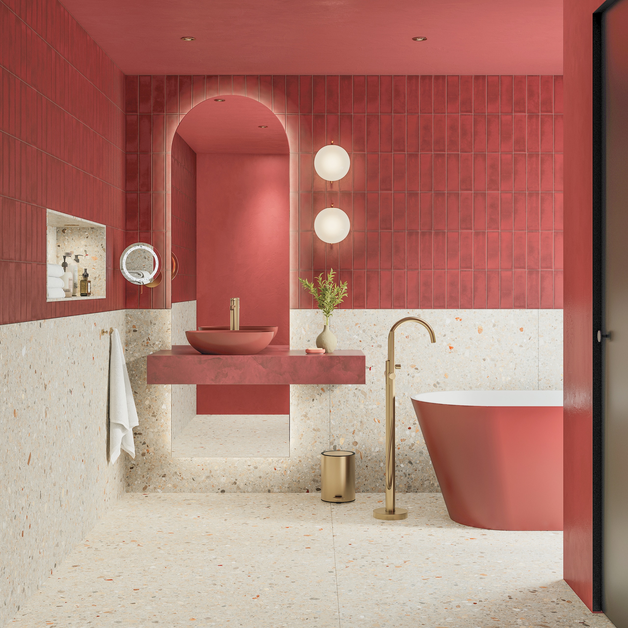 Fliesendorf zeigt ein Badezimmer mit Bronze-Armaturen, Steinwaschtisch, freistehender Badewanne, roten Stabfliesen und XXL-Fliesen in Terrazzo-Optik an Wand und Boden.