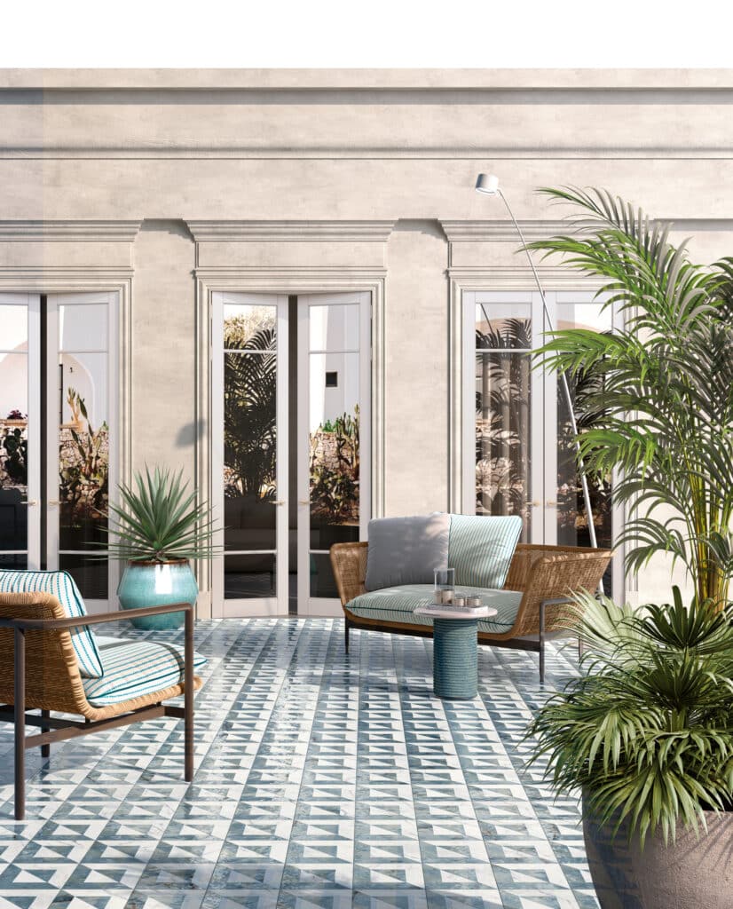 Balkon bzw. Dachterrasse eines Altbaus mit mediterranem Flair, blau-weiß gemusterten Bodenfliesen aus der Dimore-Reihe, exotischen Pflanzen und gemütlichen Möbeln von Fliesendorf.