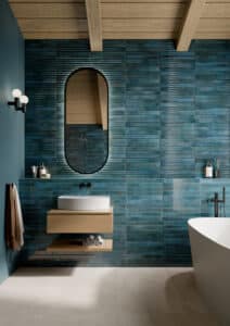 Badezimmer mit blauen Stab- und Riffelfliesen an der Wand aus der Life-Reihe von Fliesendorf, kombiniert mit warmer Holzdeckenverkleidung und hellen Bodenfliesen.