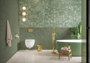 Badezimmer mit grünen Marmorwandfliesen, großformatigen hellen Steinbodenfliesen, freistehender grüner Badewanne mit Messingarmaturen von Fliesendorf.