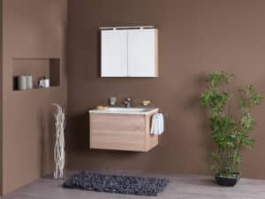 Frauenthal Handel zeigt ein Badezimmer mit einem Waschbecken, Unterschrank aus hellem Holz mit einer großen Schublade und einem eleganten Spiegelschrank mit Beleuchtung.