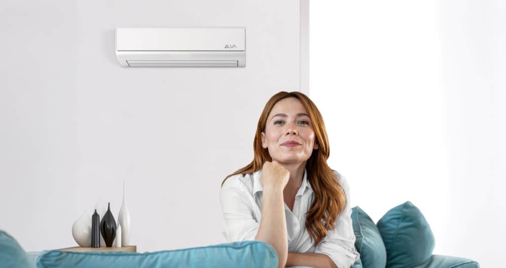 Eine Frau genießt das angenehm temperierte Wohnzimmer mit einer Klimaanlage von ALVA die kühlen und heizen kann.
