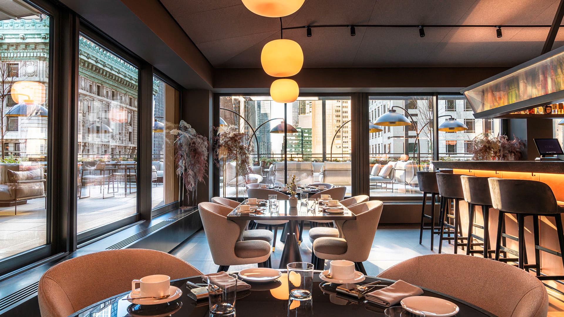 Gessi zeigt Tische im Restaurant im CORE: New York mit Blick auf die Dachterrasse.
