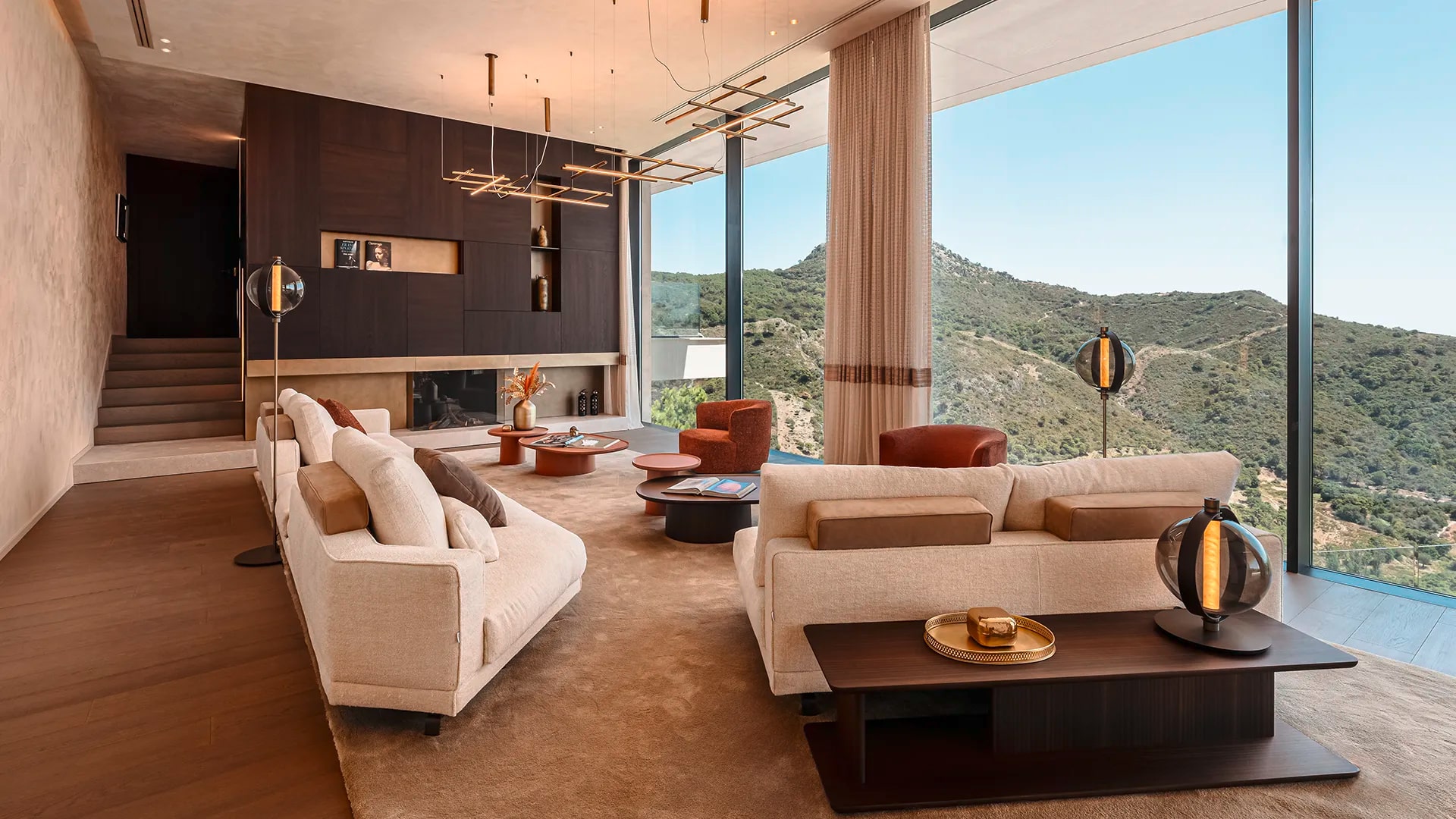Gessi zeigt den großzügigen Wohnraum in der Casa Cuiabá mit zwei Sofas, Kamin und atemberaubendem Ausblick.
