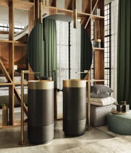 GESSI präsentiert zwei Waschbeckensäulen in hellgrau, anthrazit und gold mit freistehenden Armaturen in Gold mit aufgerauhtem Drehhebel.