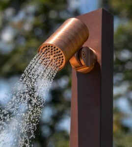 GESSI zeigt den schwenkbaren Duschkopf der freistehenden kupferfarbenen Duschsäule.