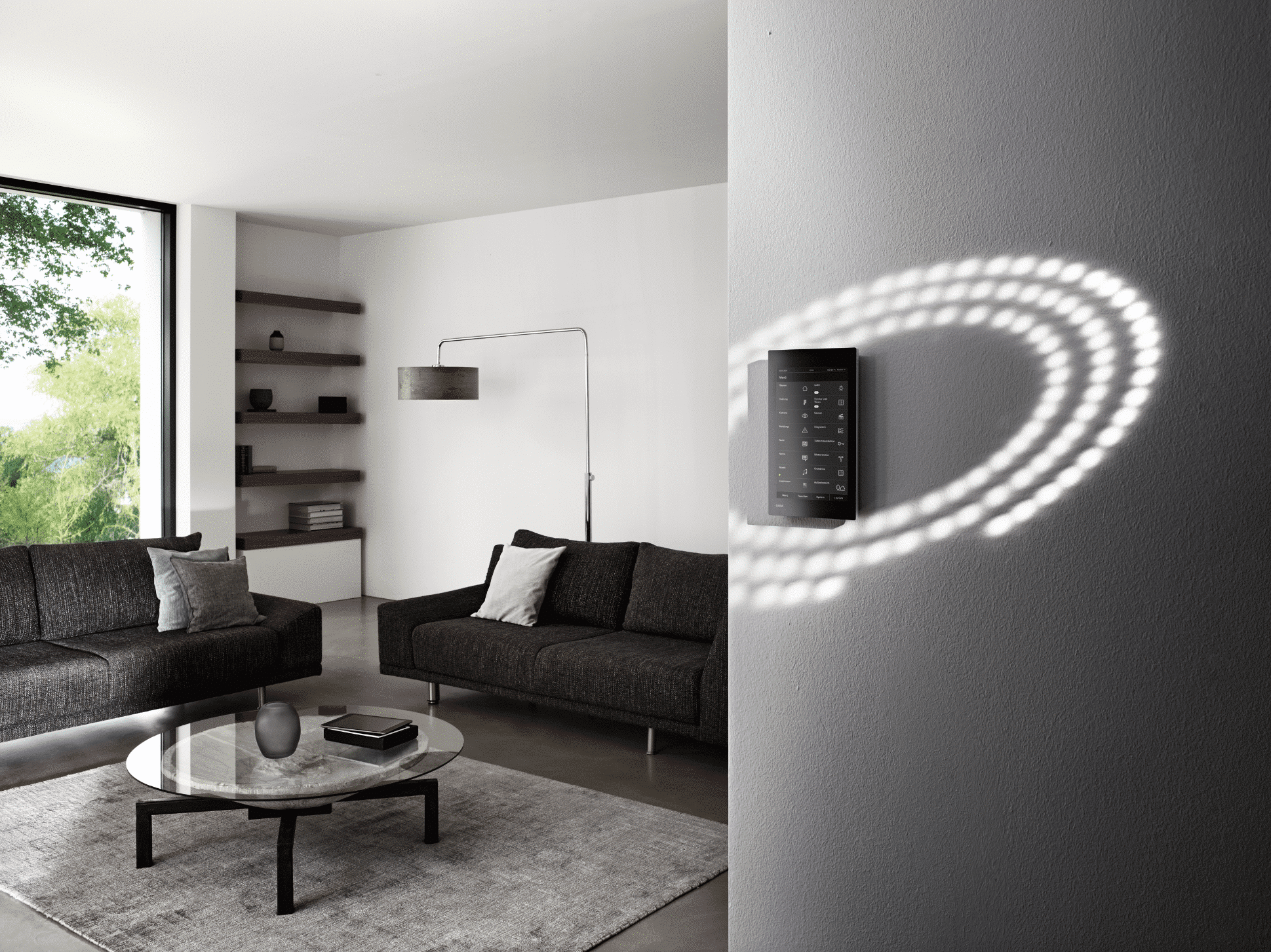 Gira zeigt eine schwarze Smarthome Fernbedienung mit Touchscreen mit der man unter anderem Lichteinstellungen in Wohnräumen verändern kann.