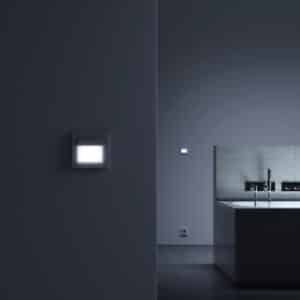 Ein beleuchteter Bewegungsmelder/Sensor namens 'Sensotec' im Badezimmer zur automatischen Erfassung von Bewegung und Steuerung von Licht oder Funktionen im Raum von Gira.