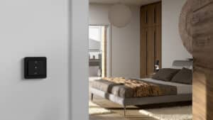 Ein schwarzes KNX‑RF‑Multi‑Bedienelement im Schlafzimmer zur Steuerung verschiedener Smart‑Home‑Funktionen von Gira.