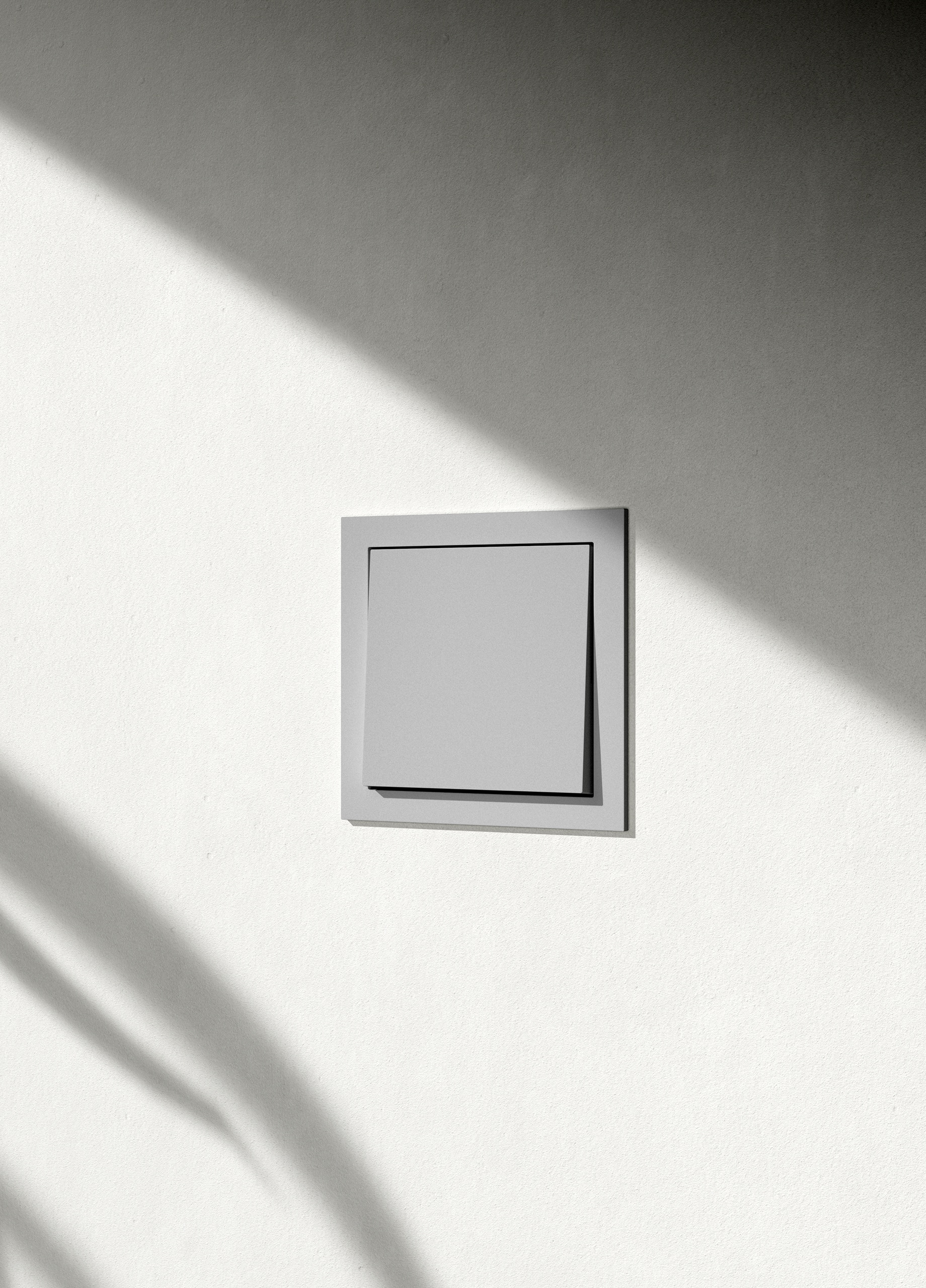Ein Gira F200 flach Wippschalter in Schattengrau mit schlankem Rahmen an einer hellen Wand.
