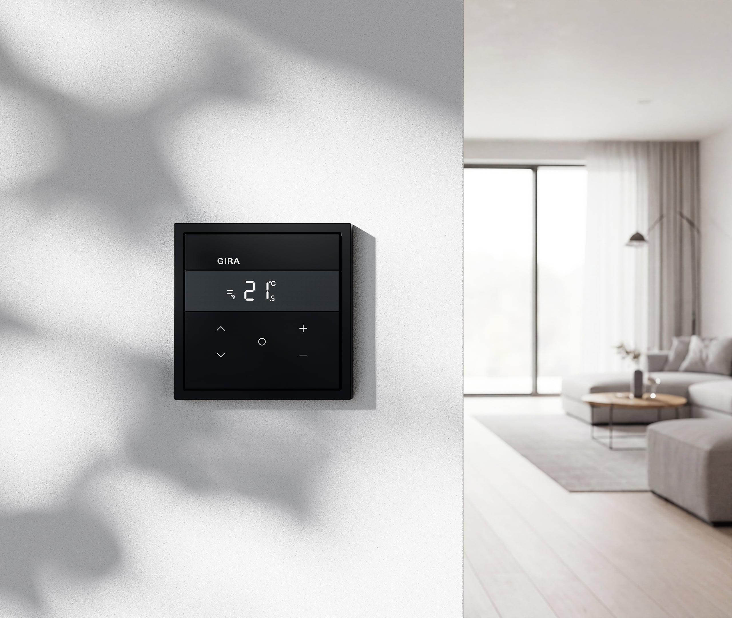 Ein Gira Temperaturregler F300 RKS HLK KNX in Schwarz an einer hellen Wand im Wohnzimmer.