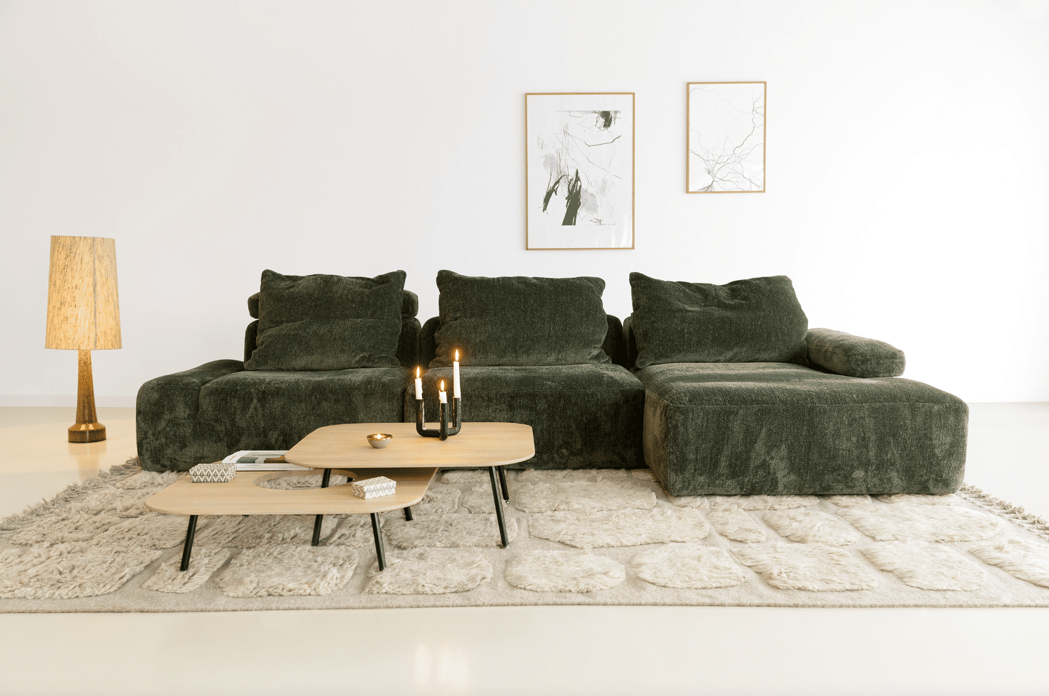 WOHNHAUS Grill & Ronacher zeigt ein helles Wohnzimmer mit einem khakigrünem Sofa und einem Beistelltisch aus Holz auf einem gemusterten, freiliegenden Teppich von SITS.