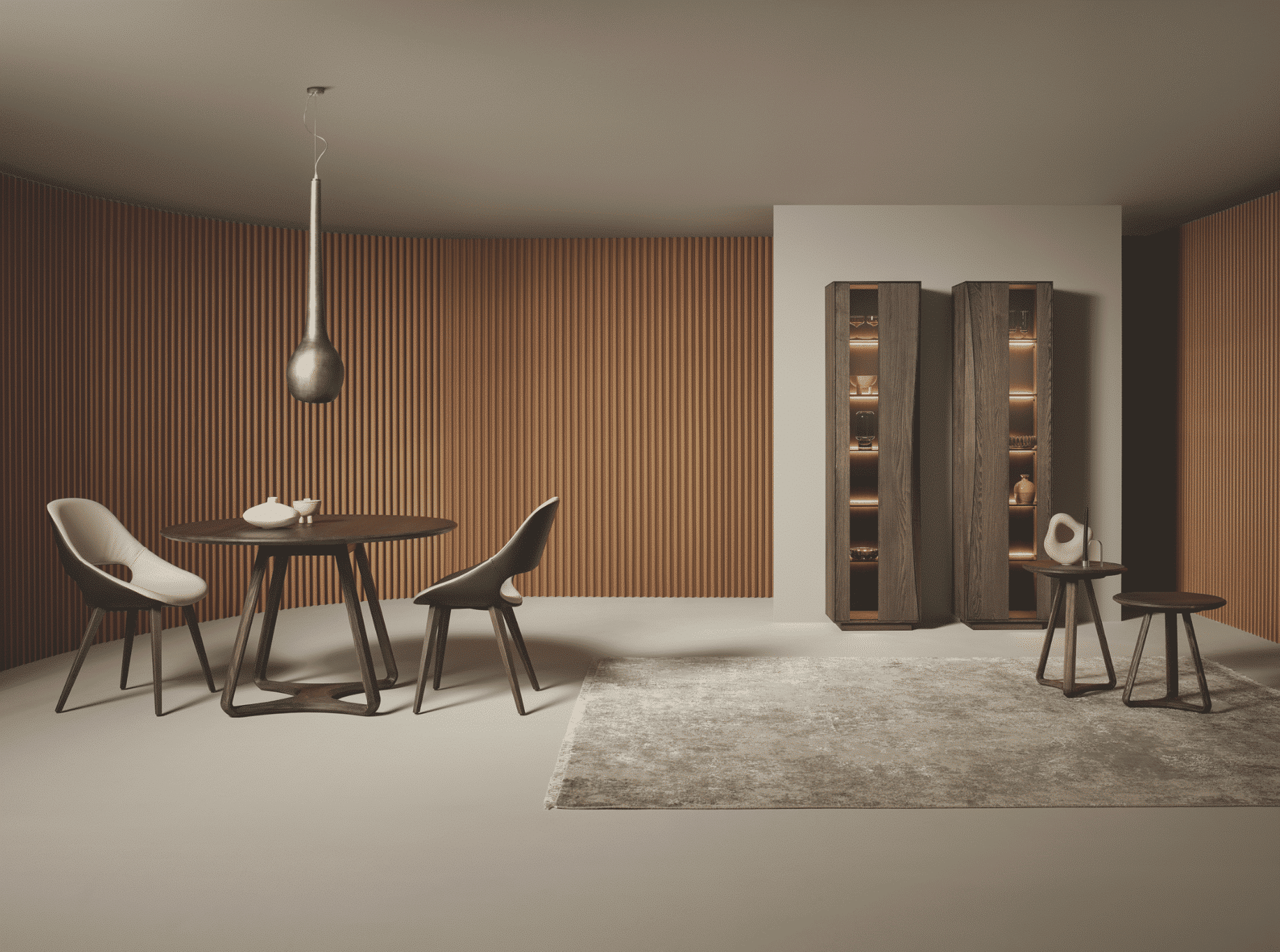 WOHNHAUS Grill & Ronacher zeigt ein Esszimmer mit einem Holztisch und einer silbernen Hängelampe darüber, braunen Stühlen mit heller Sitzfläche und zwei hohen Holzregalen an der Wand und einem freiliegendem Teppich von Anrei.