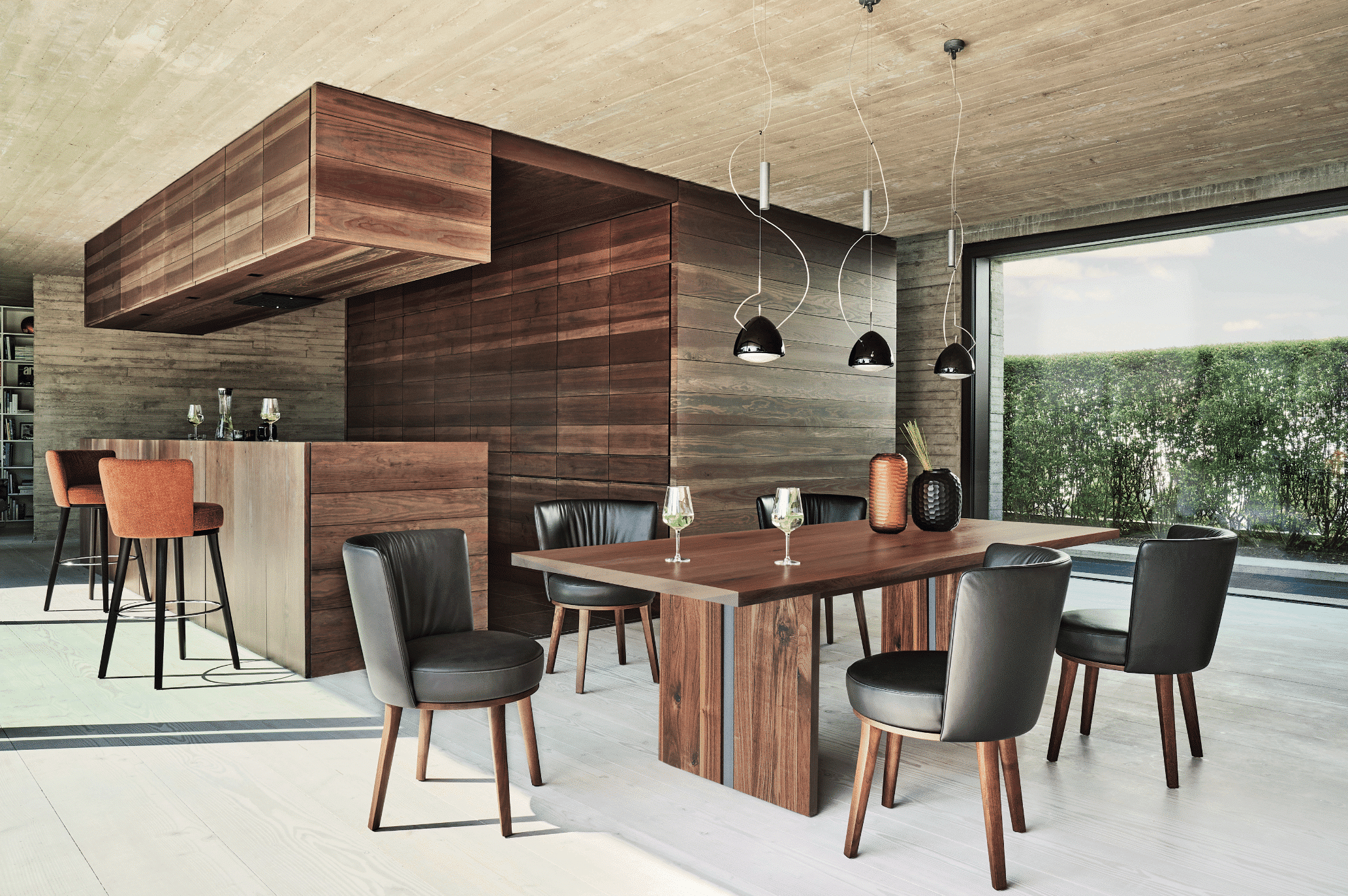 WOHNHAUS Grill & Ronacher zeigt ein Esszimmer mit schönem Holztisch und schwarzen Lederstühlen und angrenzender Bar aus edlem Holz mit Sitzhockern von Bielefelder Werkstätten.