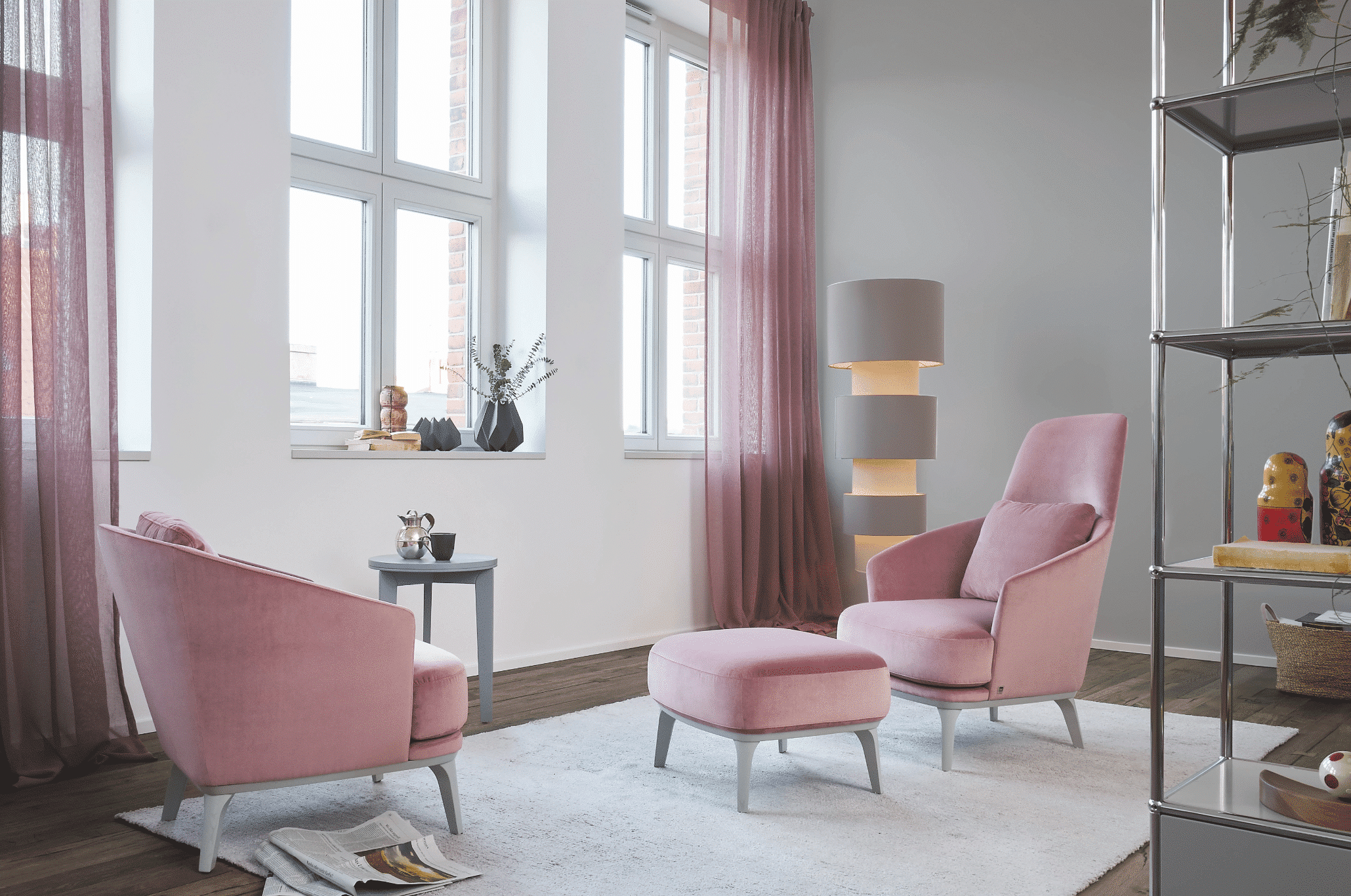 WOHNHAUS Grill & Ronacher zeigt ein Lesezimmer mit gemütlichen Polsterstühlen in rosa und passendem Hocker auf einem freiliegendem Teppich und einer Stehlampe von Bielefelder Werkstätten.