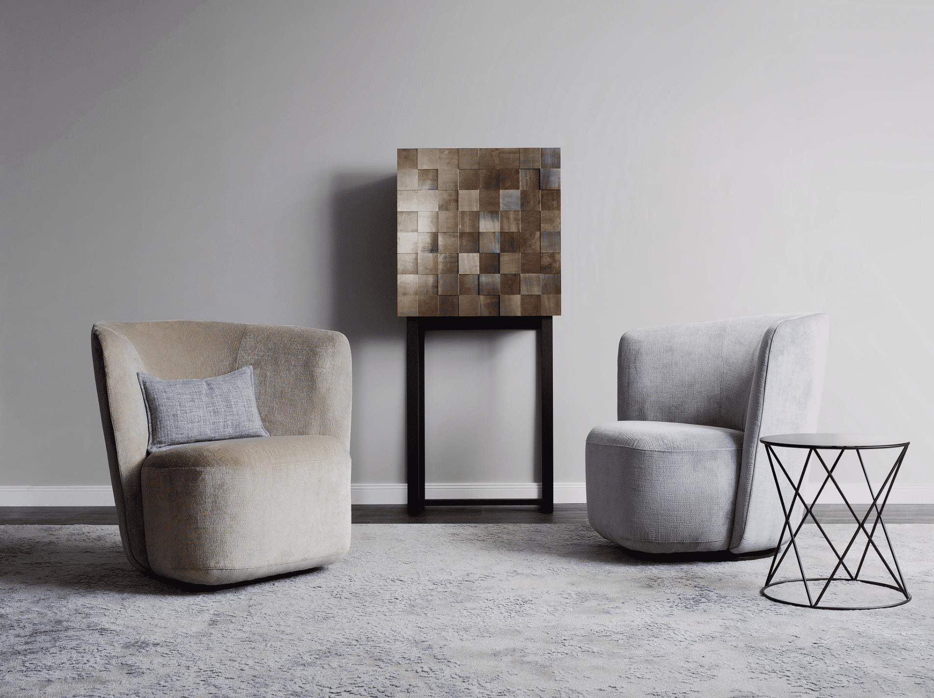 Ein Einzelsofa in helbraunem Samt und ein Einzelsofa in hellgrauem Samt mit modernem Beistelltisch und einem Schrank auf hohen Möbelbeinen mit einer Front in Mosaik-optik von Christine Kroencke Interior Design präsentier von Grill & Ronacher.