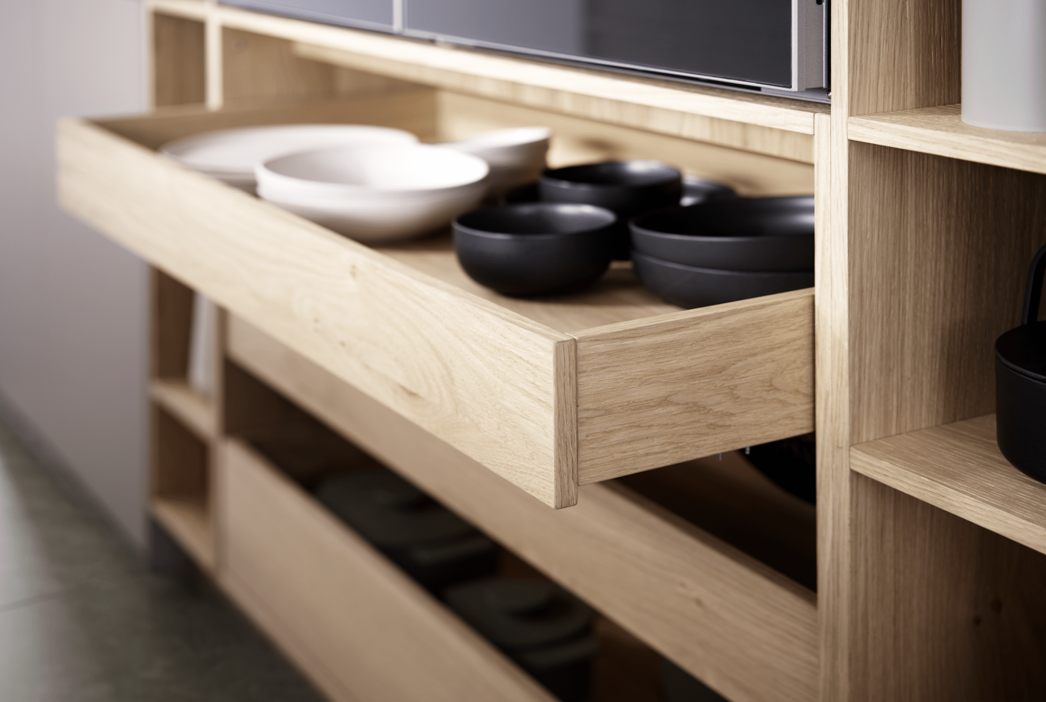 Eine grifflose, offene Küchenschublade aus Holz von Leicht Küchen präsentiert von Grill & Ronacher.