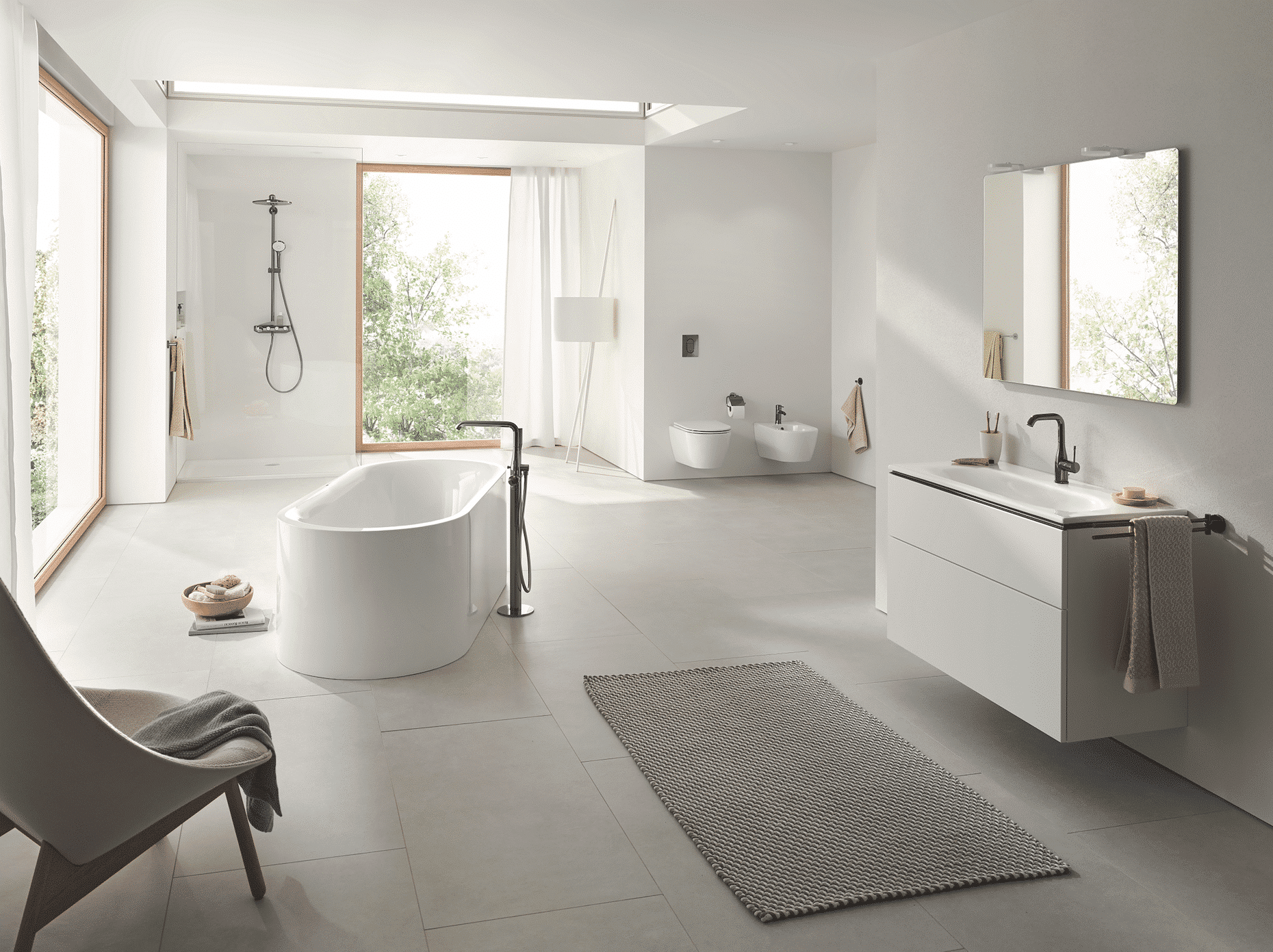 Grohe zeigt ein lichtdurchflutetes Badezimmer in Naturtönen mit einer freistehenden Badewanne, offener Dusche und weissem Waschtisch mit silbernen Armaturen und Fliesenboden.