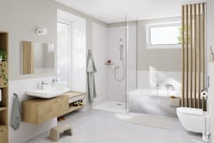 Helles Badezimmer mit Waschtisch aus hellem Holz, aufgesetztem Waschbecken, Badewanne, Dusche mit Glaswand und WC mit silbernen Armaturen und Halterungen von Grohe.